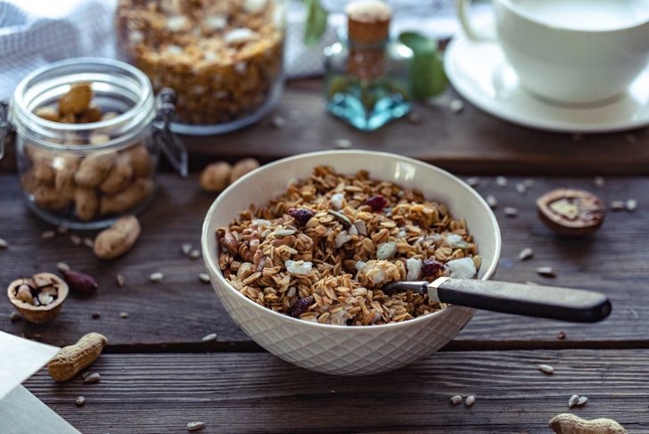 Healthy lifestyle breakfast bowl plate with granola and spoon on brown wooden table background, cereal granola food with nuts seed organic muesli morning diet oat meal for health care concept