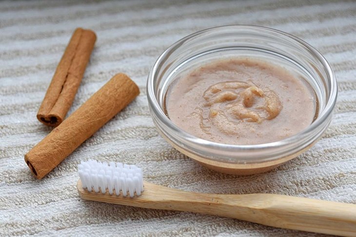 Homemade cinnamon, baking soda and coconut oil toothpaste, eco friendly bamboo toothbrush, close up view.