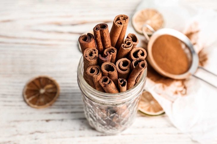 Jar with aromatic cinnamon sticks on wooden background