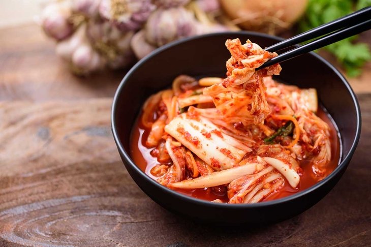 Eating kimchi cabbage in a bowl with chopsticks, Korean food