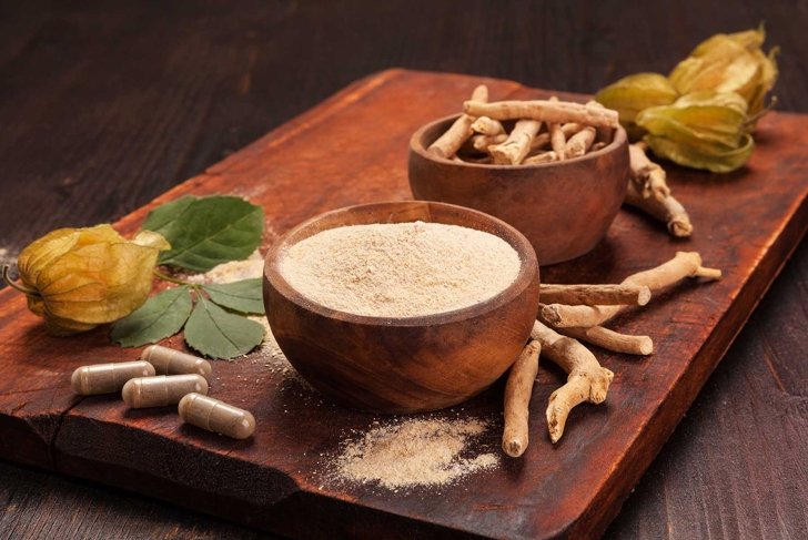 Roots and powder of Ashwagandha also known as Indian ginseng on wooden background. Hair loss, anti cancer, testosteron and depression benefits.