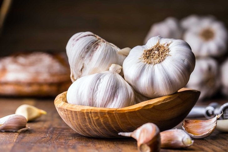 Garlic Cloves and Bulb in vintage wooden bowl.